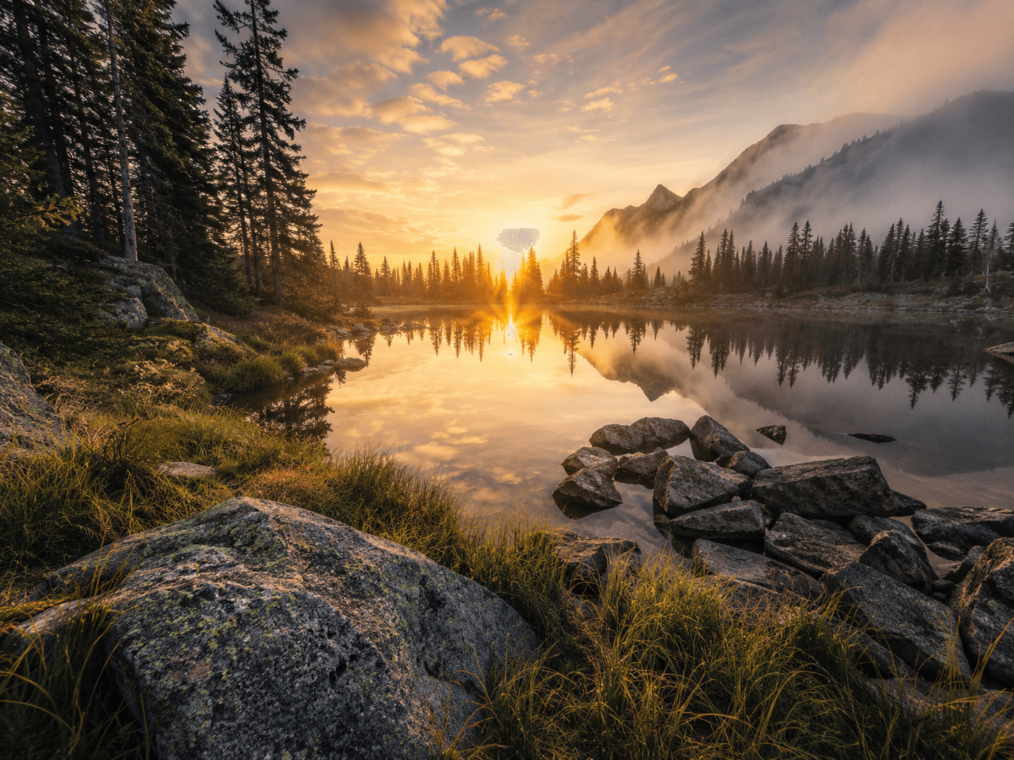 Au bord d’un lac calme, les premières lueurs du jour traversent les montagnes et se reflètent dans l’eau. Cette image célèbre la puissance tranquille de la nature, entre silence, brume et lumière naissante.